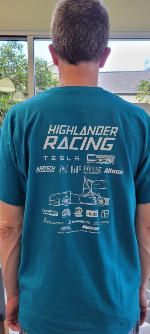 A person wearing a blue shirt with logos on it.