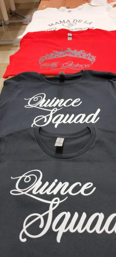 A bunch of tshirts kept on top of each other with quince squad written.